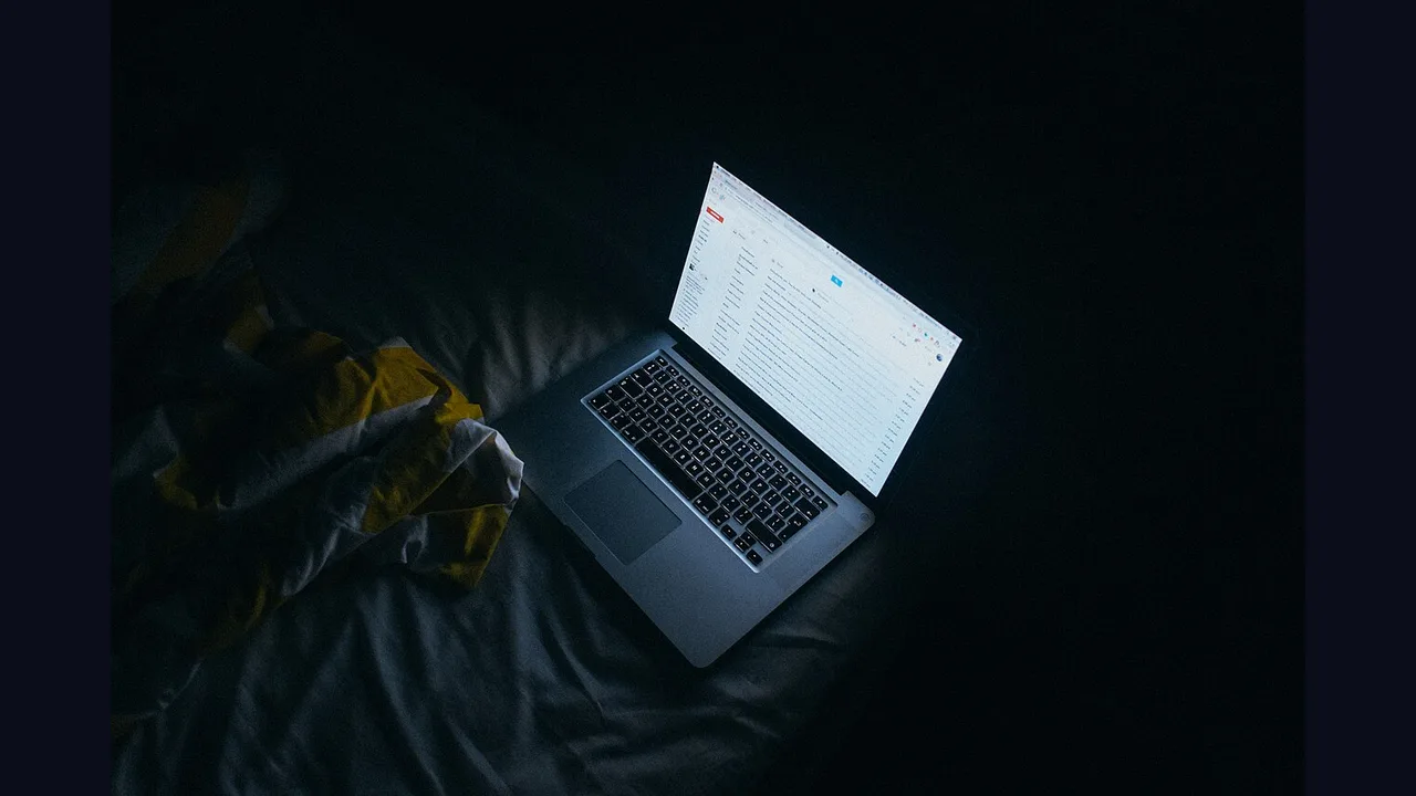 A laptop glowing on a bed at night