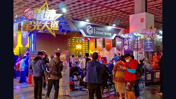 An esports stage with players at computers and a large screen